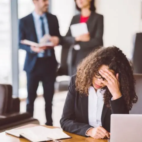 woman stressed out at work with co-workers in the background